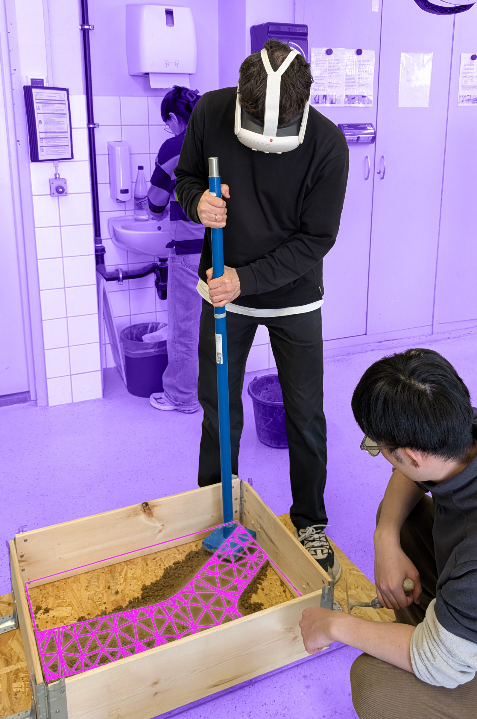A headset user manually compacts earth in timber formwork, with the target geometry overlaid in augmented reality.